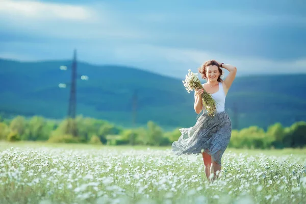 Geniş bir alanda papatyaları olan mutlu yetişkin bir kadın. — Stok fotoğraf