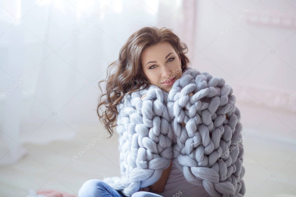 A young woman with a beautiful hairdo sits wrapped in a warm blue plaid