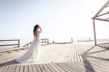 Bulutların üstündeki dağın tepesinde beyaz elbiseli bir gelin. Fotoğraf tam gelişim