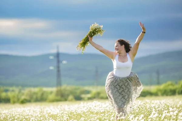 Mladá žena 30 let v sukni sbírá sedmikrásky v terénu — Stock fotografie