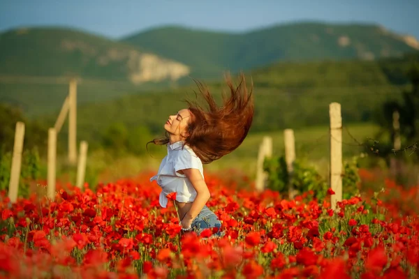A woman in a rural scene in the meadow in a field of poppies. — ストック写真