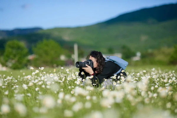 Fotograf przykucnął w wysokiej trawie, by zrobić piękne zdjęcie. — Zdjęcie stockowe