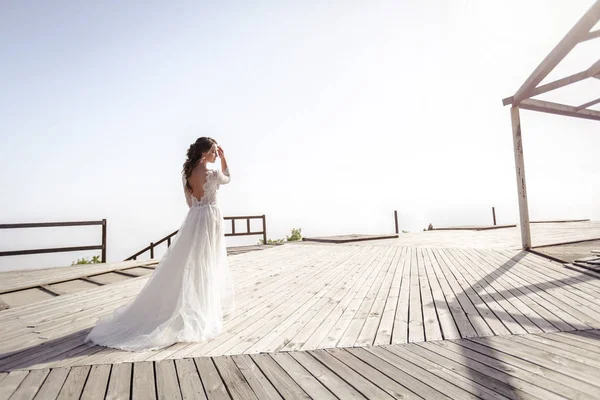 Una sposa vestita di bianco sulla cima di una montagna sopra le nuvole. Foto in piena crescita — Foto Stock