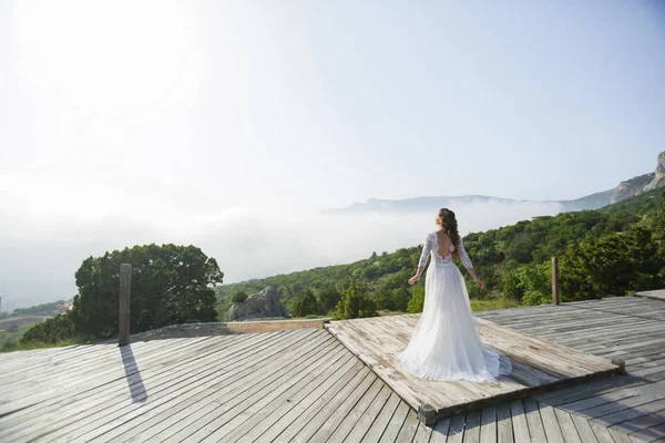 A woman bride in a white long wedding dress alone in the photo at the top of the mountain. Copy space — 스톡 사진