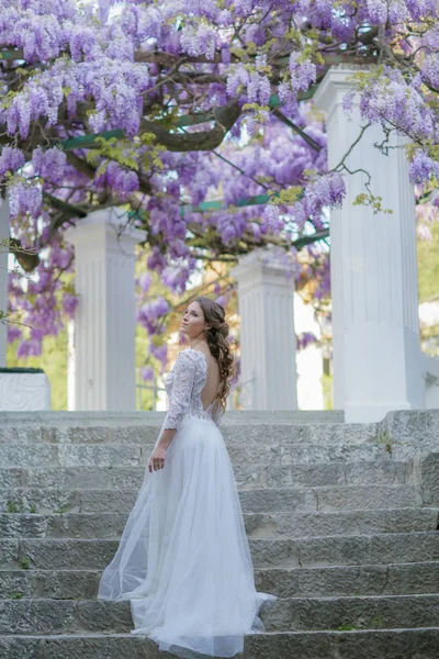 Mulher nas escadas sob uma árvore Wisteria com flores lilás — Fotografia de Stock