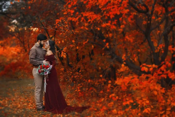 Nell'autunno di una donna con un uomo che si abbraccia nel Parco con alberi rossi — Foto Stock