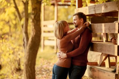 Bir adam sevgilisini gölün yakınındaki bir ormanın yakınında tutkuyla kucaklıyor.