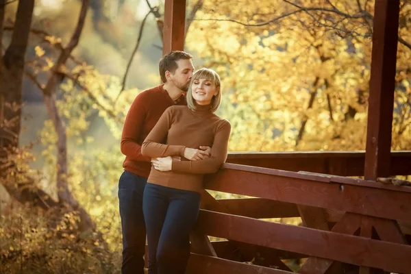 Um homem abraça apaixonadamente sua amada mulher perto de um eixo na floresta perto do lago — Fotografia de Stock