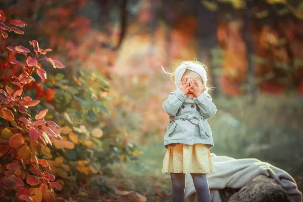 Ein kleines Mädchen spaziert in einem öffentlichen Park mit Bäumen und hält ein Lieblingsspielzeug in der Hand — Stockfoto