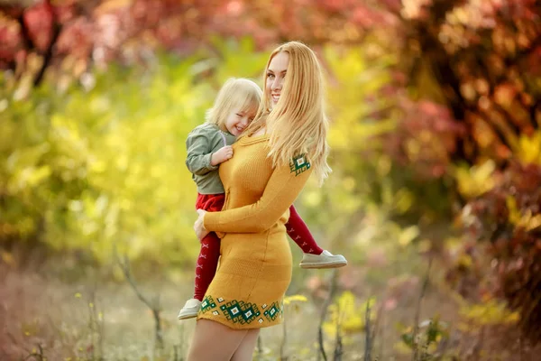 Молодая мать обнимает свою маленькую дочь и носит ее на руках в лесу — стоковое фото