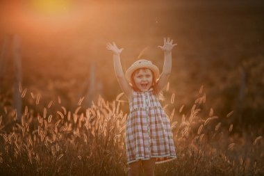 Arka planda hill ile bir elbiseyle alanları günbatımı güneş ışığı ile oynayan genç sarışın kız