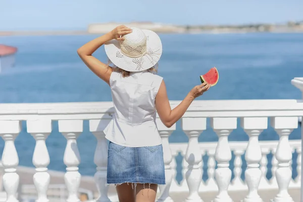 Μια γυναίκα το καλοκαίρι με μια άσπρη μπλούζα με μια φέτα καρπούζι στα χέρια της — Φωτογραφία Αρχείου