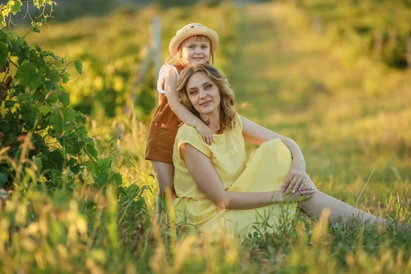Mamma är en vuxen kvinna som kramar ett barn på ett gränslöst grönt fält. — Stockfoto