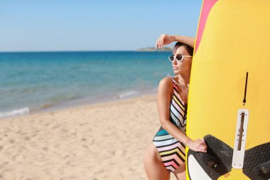 Spor mayo ve kumlu güneş gözlüğü takmış bir sörf sporcusu.