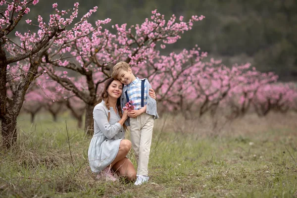Moeder met kind in een lente in bloeiende tuin — Stockfoto