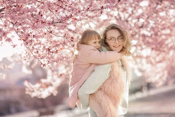 Anne bahçede yürürken bebeğe sarılıyor. — Stok fotoğraf