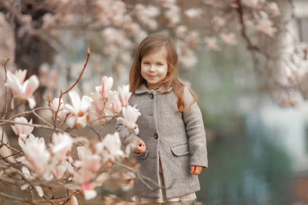 Ett barn nära blommorna i mognolia. — Stockfoto
