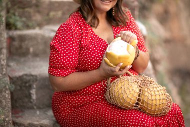 Bir kadın taş basamaklara oturur ve olgun bir üzüm meyvesini temizler.