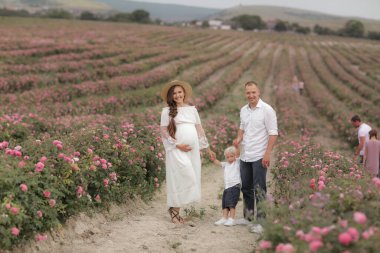 Üç kişilik bir aile yaban gülü tarlasında yürüyor.