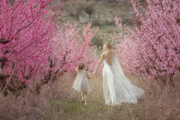 A woman dressed in a dress goes with a baby between the trees — Stock Photo, Image