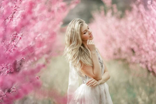 Mooie vrouw gekleed in een jurk tegen de achtergrond van bomen — Stockfoto