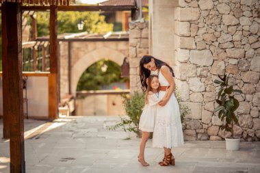 Doğu görünümünün genç ve güzel annesi kızıyla birlikte Akdeniz 'in antik sokaklarında yürüyor.