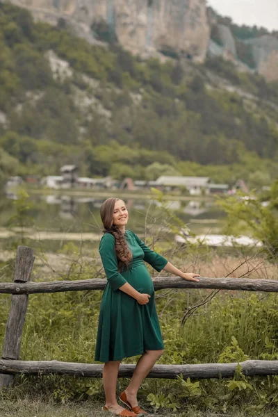 Donna incinta in una passeggiata estiva fuori città vicino al lago di montagne e foreste — Foto Stock