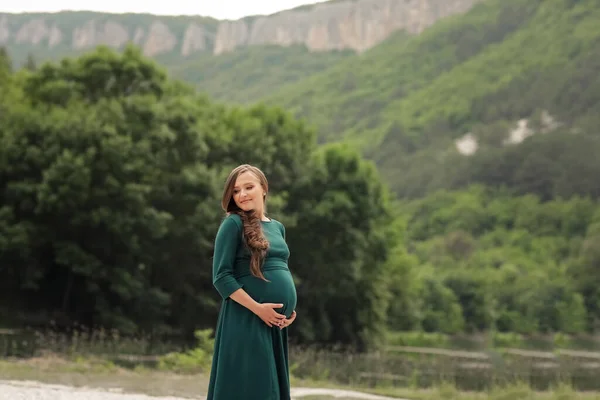 Terhes nő egy nyári séta a városon kívül, közel a tó a hegyek és erdők — Stock Fotó