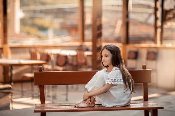 A child with bare feet sits on a wooden bench. — Stock fotografie