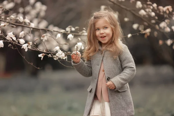 Flicka 3-4 år gamla sniffar blommor av blommande träd — Stockfoto