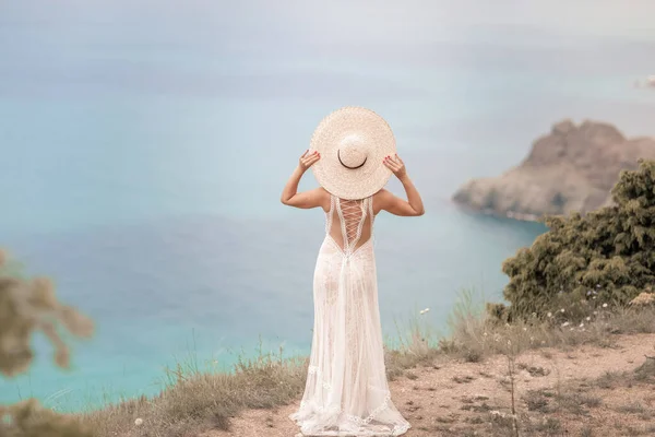Balayı sırasında uzun beyaz elbiseli bir kadın denizin üstündeki dağlarda yürüyüşe çıktı. — Stok fotoğraf