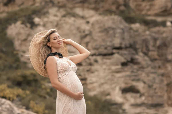 The bride on a romantic walk during pregnancy in the summer walks on the rocks — Stock fotografie