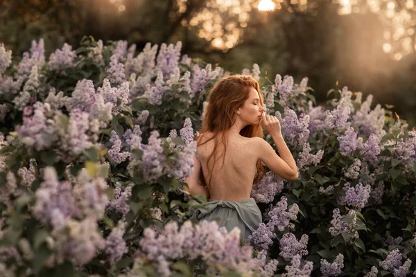 Жінка з довгим рудим волоссям серед квітів — стокове фото