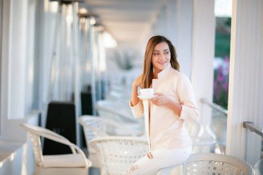 Bir kadın masaya oturur ve kahve içer.