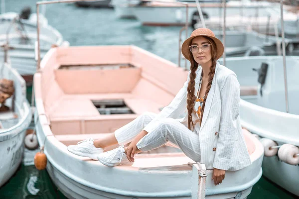 Beyaz takım elbiseli genç bir kız bir zevk teknesinin arkasında oturuyor. — Stok fotoğraf