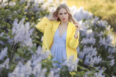 Etrafı leylak çiçekleriyle çevrili genç bir kız