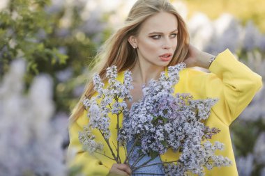 Etrafı leylak çiçekleriyle çevrili genç bir kız