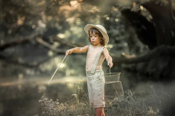 Un niño cerca del río con un palo en las manos como con una caña de pescar . — Foto de Stock