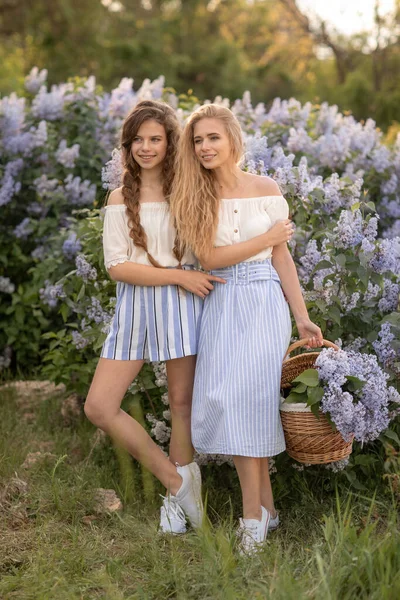 Дві молоді дівчата, одягнені в красивий одяг, стоять проти б — стокове фото