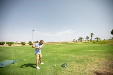 Golf sahasındaki bir adam ekipmanları inceler ve golf kulübündeki spor müsabakasına hazırlanır.