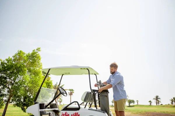 Un hombre monta un campo de golf en un carrito de golf — Foto de Stock