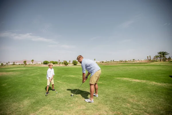 아버지는 재미있게 놀면서 아들에게 푸른 잔디 위에서 골프치는 법을 가르친다 — 스톡 사진
