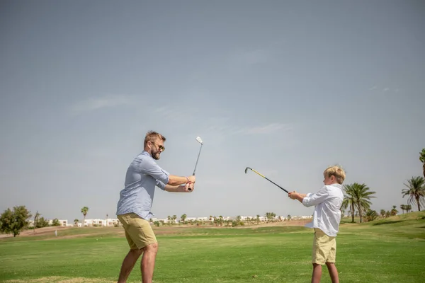 아버지는 재미있게 놀면서 아들에게 푸른 잔디 위에서 골프치는 법을 가르친다 — 스톡 사진