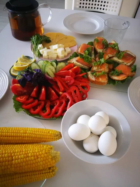 Huevos cocidos en cáscara, maíz amarillo cocido, sándwiches con rodajas de salmón y avena fresca para el desayuno — Foto de Stock