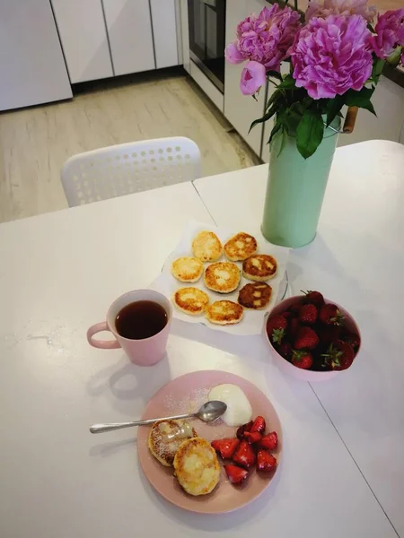 新鲜的糕点和一杯咖啡，明天放在桌上，上面点缀着鲜花 — 图库照片