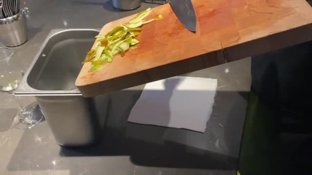 Il cuoco rimuove i resti della frutta sbucciata con un coltello da un tagliere di legno — Video Stock