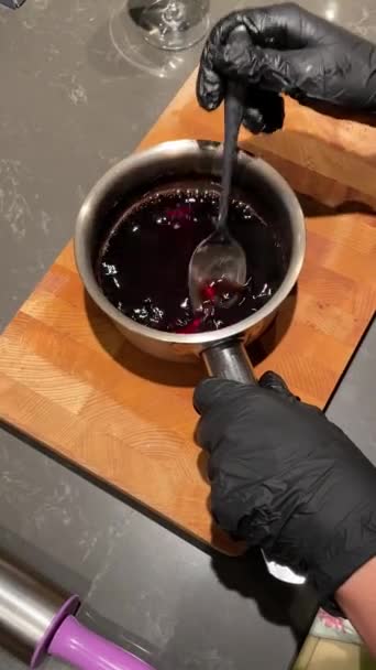 Una donna prepara sciroppo di vino e mescola il vino bollito in un mestolo di metallo — Video Stock