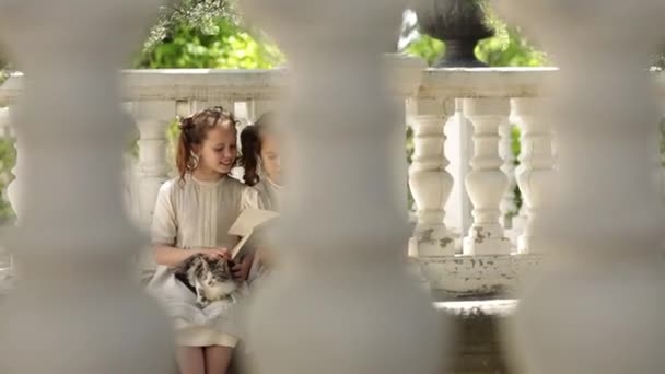 Dos niñas son estudiantes en un internado estudiando y leyendo un libro en el parque — Vídeo de stock