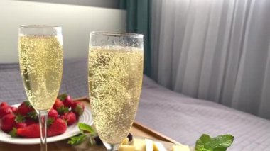 Komodinin yanında iki bardak şampanya ve tatlı bir tatlı.