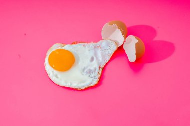 Çırpılmış yumurta, pembe arka plandaki kırık kabuklardan kaynaklanır.